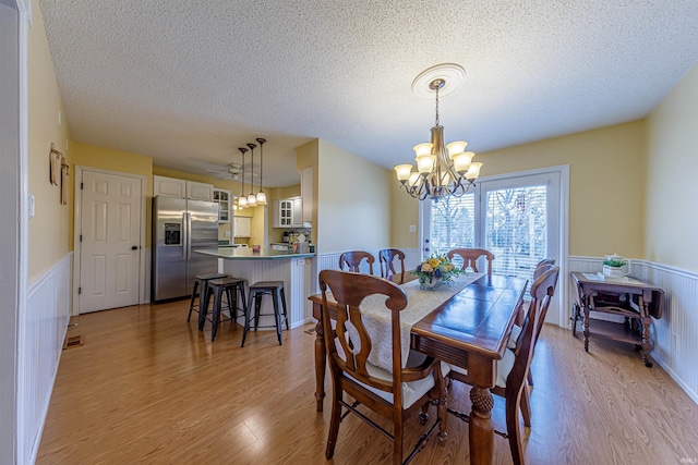 dining room featuring a textured ceiling, light hardwood / wood-style flooring, and a notable chandelier