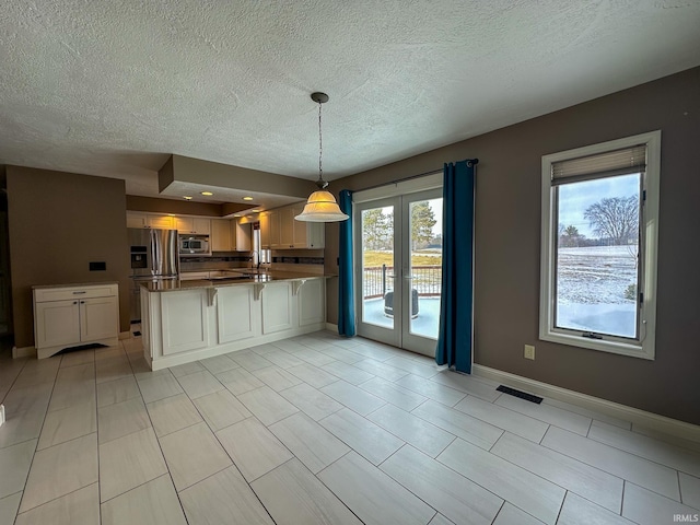 kitchen with visible vents, appliances with stainless steel finishes, a peninsula, white cabinetry, and pendant lighting