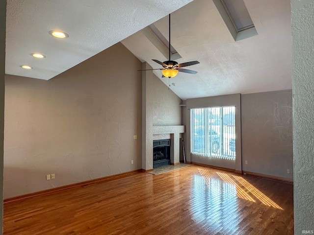 unfurnished living room with a fireplace with flush hearth, vaulted ceiling, baseboards, and wood finished floors