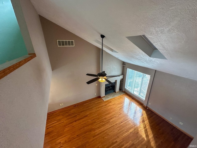 unfurnished living room featuring visible vents, vaulted ceiling, a textured ceiling, and wood finished floors