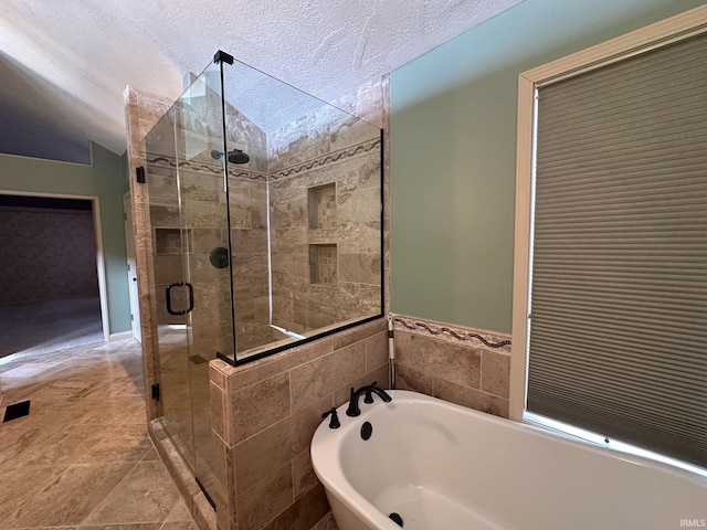 bathroom featuring a textured ceiling, a shower stall, and a bathing tub