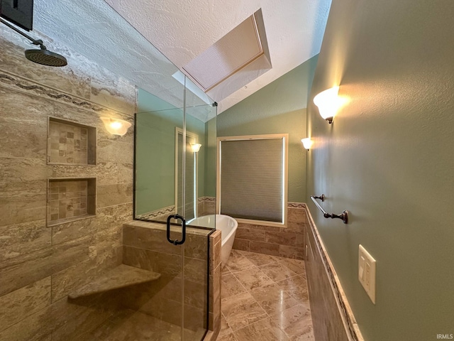 bathroom featuring a stall shower, lofted ceiling, a freestanding tub, and a textured ceiling