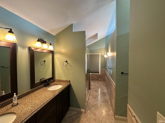 full bathroom featuring double vanity, a shower stall, vaulted ceiling, and a sink