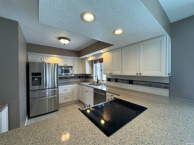 kitchen featuring appliances with stainless steel finishes, white cabinets, a sink, and backsplash