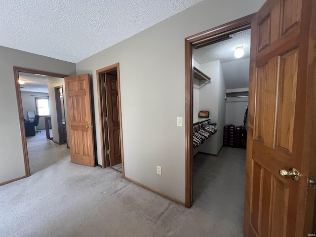 bedroom with a spacious closet, light colored carpet, a textured ceiling, and a closet