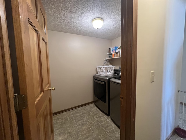 washroom with dark tile patterned flooring, washer and clothes dryer, and a textured ceiling