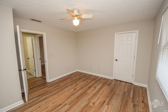 empty room featuring ceiling fan, a textured ceiling, and light wood-type flooring