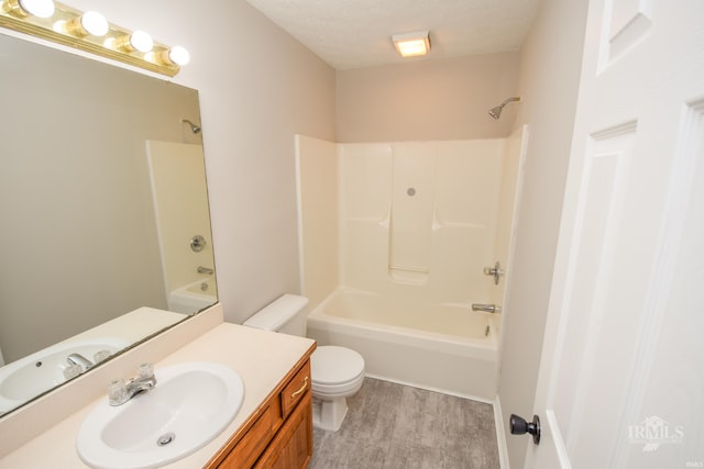 full bathroom featuring bathtub / shower combination, toilet, wood-type flooring, a textured ceiling, and vanity