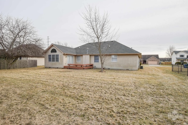 rear view of house featuring a wooden deck and a lawn