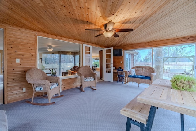 sitting room featuring wood ceiling, ceiling fan, carpet floors, and wood walls