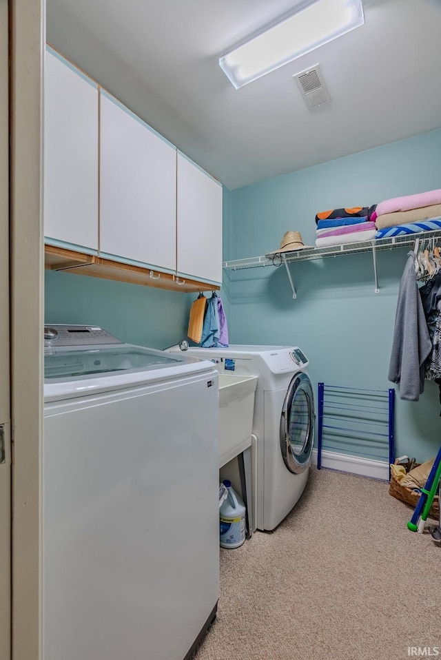 washroom with cabinets, separate washer and dryer, sink, and light carpet