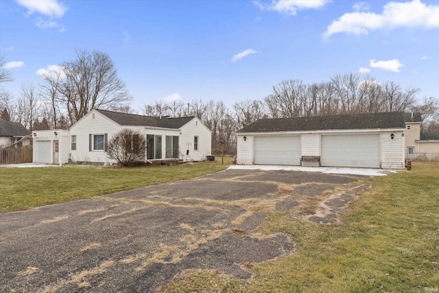 single story home with a garage, an outbuilding, and a front lawn