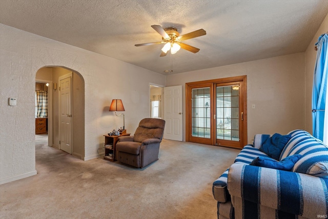 carpeted living room with ceiling fan and a textured ceiling