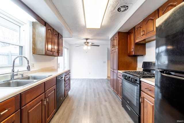 kitchen featuring sink, a textured ceiling, ceiling fan, light hardwood / wood-style floors, and black appliances