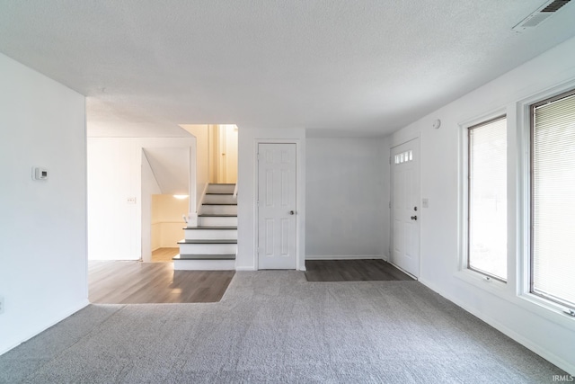 carpeted entrance foyer featuring a textured ceiling