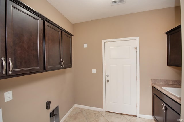 clothes washing area with cabinets, hookup for an electric dryer, sink, and light tile patterned floors