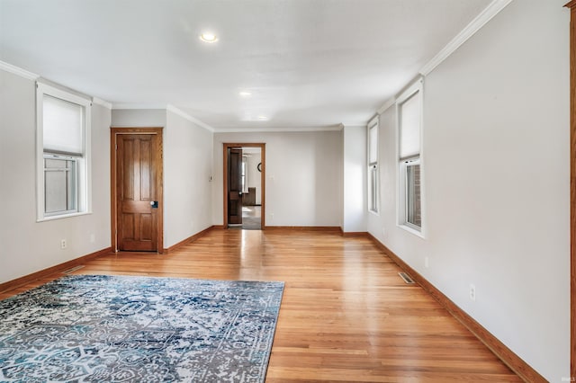 spare room with a healthy amount of sunlight, ornamental molding, and light hardwood / wood-style floors