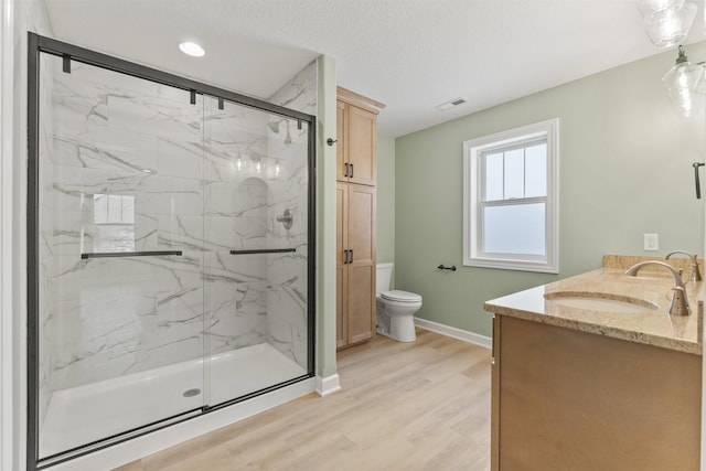 bathroom with toilet, an enclosed shower, a textured ceiling, vanity, and hardwood / wood-style floors