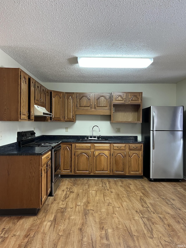 kitchen with sink, stainless steel fridge, range with electric cooktop, a textured ceiling, and light wood-type flooring