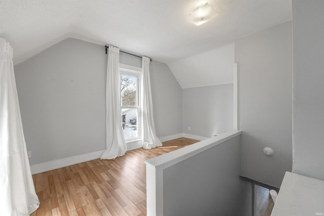 additional living space featuring lofted ceiling, hardwood / wood-style floors, and a textured ceiling