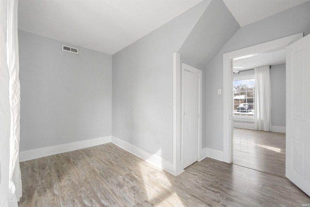 empty room featuring light hardwood / wood-style flooring and vaulted ceiling