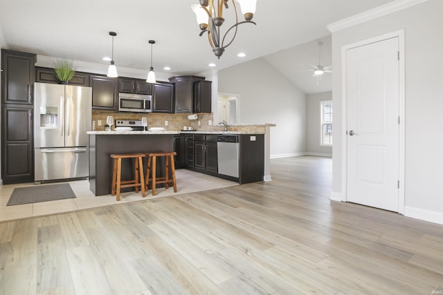 kitchen with a kitchen island, appliances with stainless steel finishes, pendant lighting, a breakfast bar area, and decorative backsplash