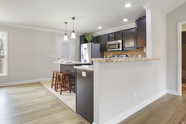 kitchen with stainless steel appliances, light stone countertops, pendant lighting, and a breakfast bar area