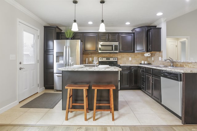 kitchen featuring appliances with stainless steel finishes, a center island, light stone countertops, light tile patterned flooring, and decorative light fixtures