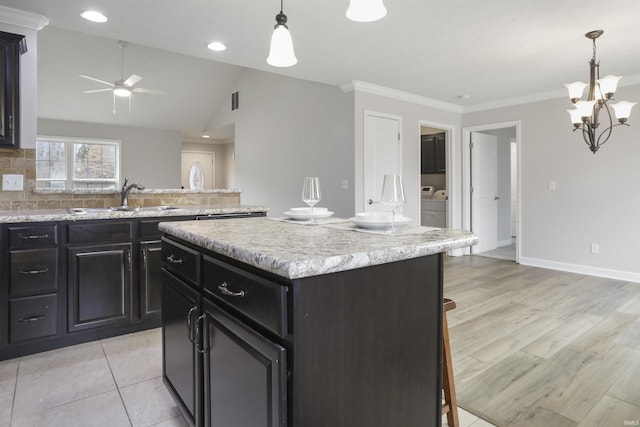 kitchen featuring sink, crown molding, a kitchen island, a kitchen bar, and decorative light fixtures