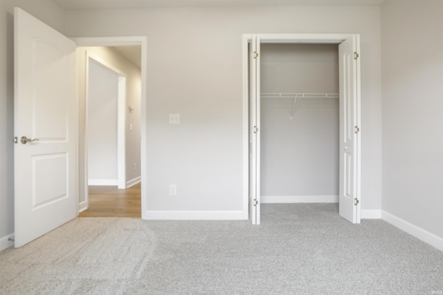 unfurnished bedroom with light colored carpet and a closet