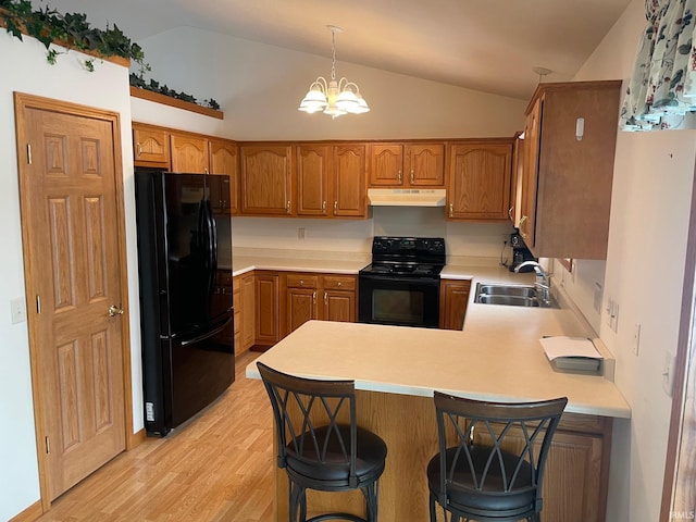 kitchen featuring pendant lighting, black appliances, sink, a kitchen bar, and kitchen peninsula