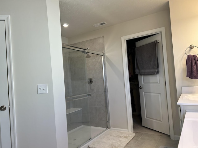 bathroom with a shower with door, vanity, and tile patterned flooring