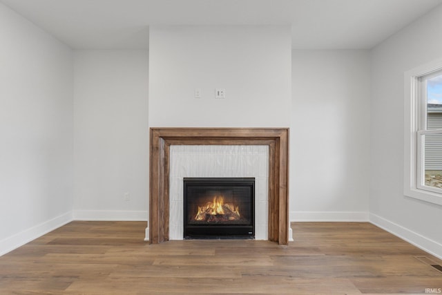 room details featuring wood-type flooring and a tile fireplace