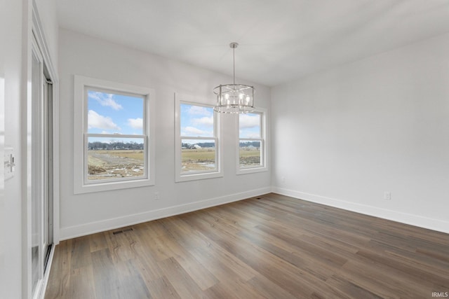 unfurnished dining area featuring a notable chandelier and hardwood / wood-style flooring