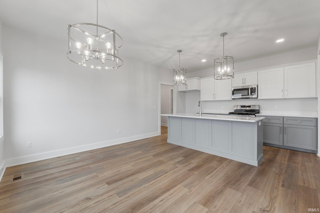 kitchen with appliances with stainless steel finishes, decorative light fixtures, a chandelier, and gray cabinetry