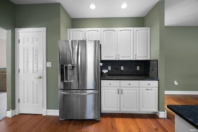 kitchen with white cabinetry, stainless steel refrigerator with ice dispenser, hardwood / wood-style flooring, and backsplash