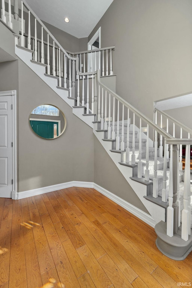 stairs featuring hardwood / wood-style flooring and a towering ceiling