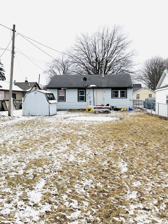 snow covered house featuring a storage shed