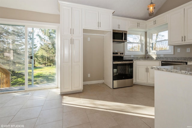 kitchen with light stone counters, light tile patterned floors, stainless steel appliances, and white cabinets