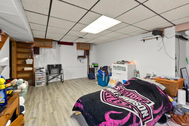 bedroom with a drop ceiling and light wood-type flooring