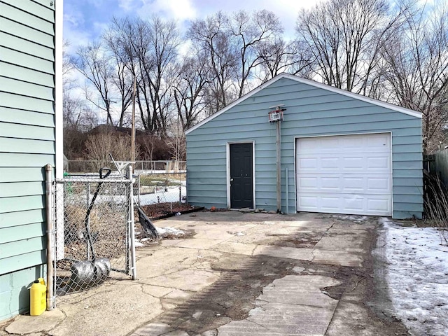 detached garage featuring driveway and fence