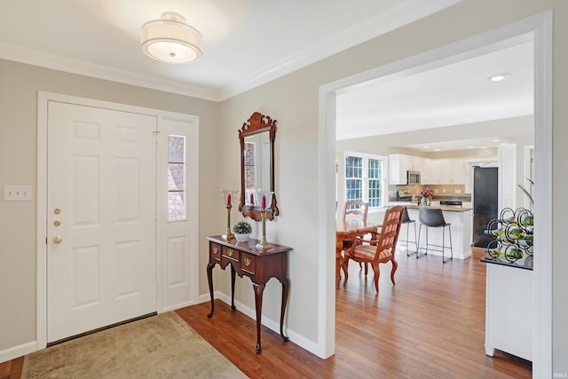 foyer entrance with ornamental molding and hardwood / wood-style floors