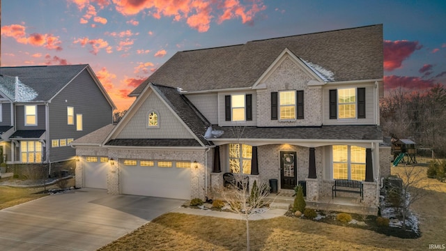 view of front of house featuring a garage, a lawn, and covered porch