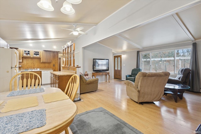 dining space featuring ceiling fan with notable chandelier, lofted ceiling with beams, and light hardwood / wood-style flooring