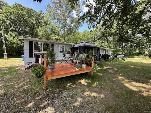 back of property with a wooden deck, a yard, a gazebo, and an outdoor fire pit