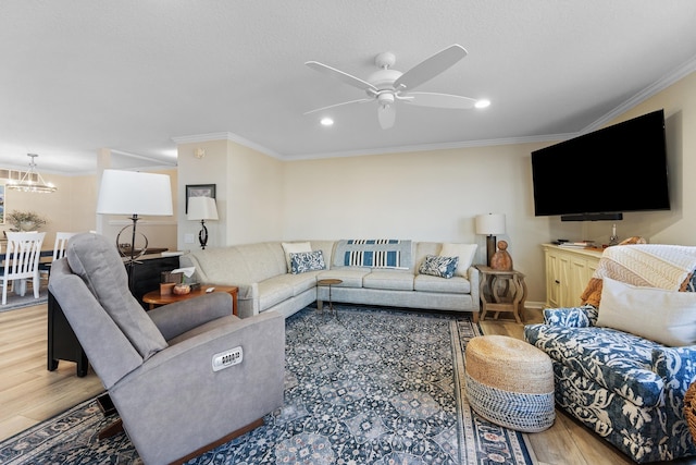 living room with hardwood / wood-style flooring, crown molding, and ceiling fan with notable chandelier