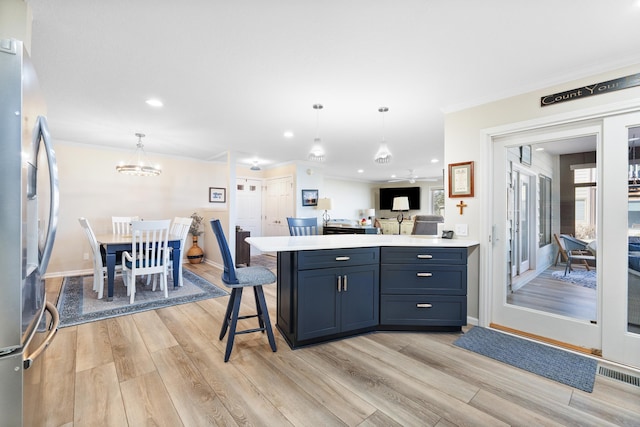 kitchen featuring crown molding, light hardwood / wood-style floors, a kitchen bar, stainless steel fridge with ice dispenser, and decorative light fixtures