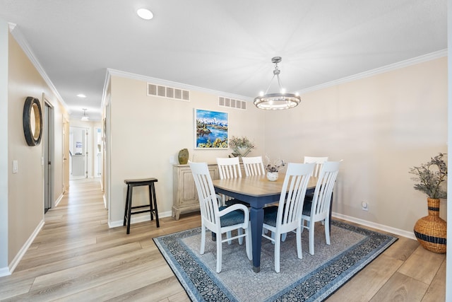 dining area with ornamental molding, light hardwood / wood-style floors, and a chandelier