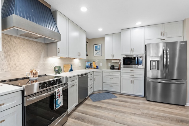 kitchen with custom exhaust hood, stainless steel appliances, light hardwood / wood-style floors, decorative backsplash, and white cabinets