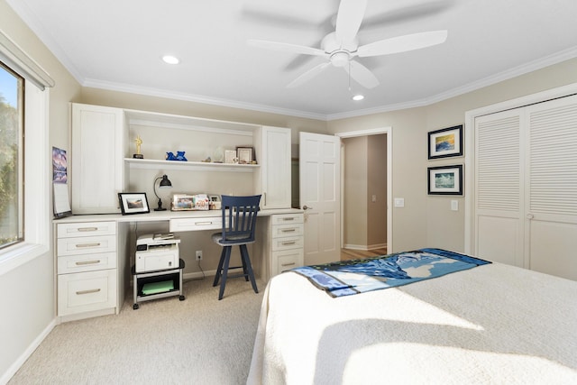 carpeted bedroom with ornamental molding, built in desk, ceiling fan, and a closet